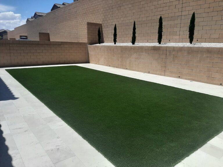 Clean artificial turf lawn bordered by travertine in a walled Las Vegas backyard