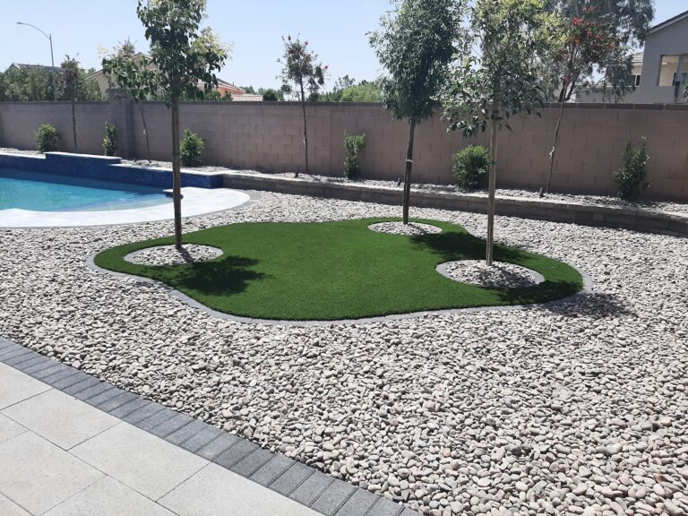 Grass converted to decorative rock with a turf island and young trees beside a pool