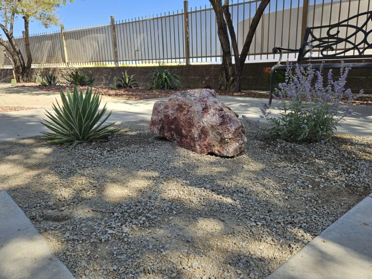 Desert landscaping with decorative rock, agave, sage and a feature boulder