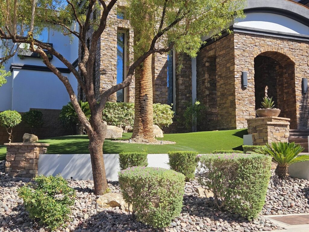 Stone-front Las Vegas home with desert shrubs, decorative rock and artificial turf installed by FreshStart Landscaping